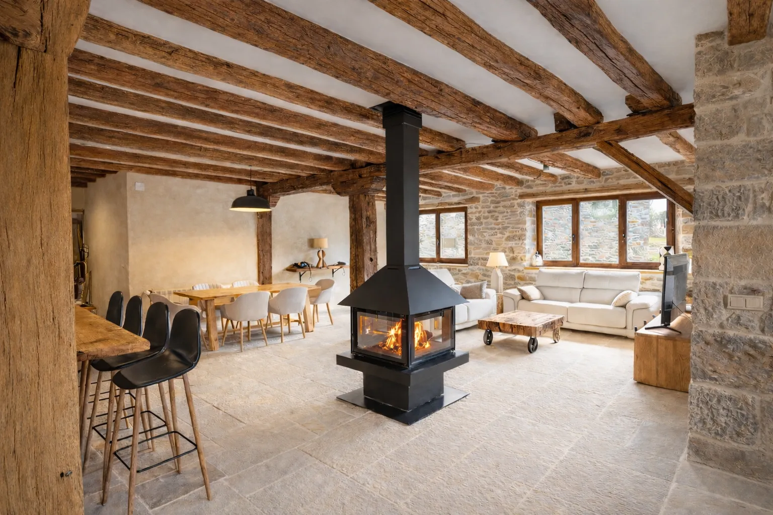 Salón abierto con chimenea central de diseño a cuatro caras en casa rural Cumbres de Lores